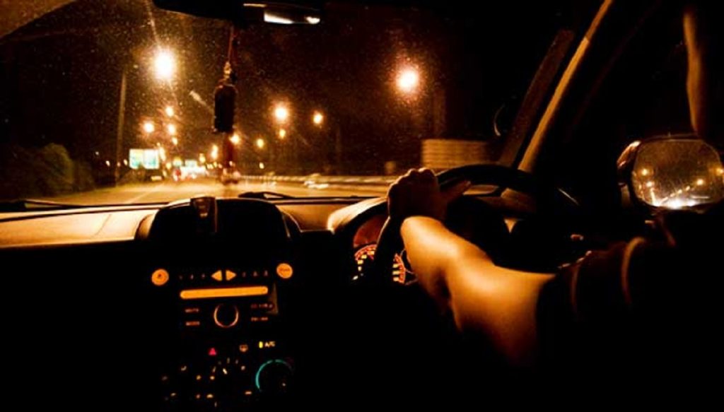 Pengemudi melintasi jalan yang lengang pada dini hari dilihat dari dalam kabin kendaraan