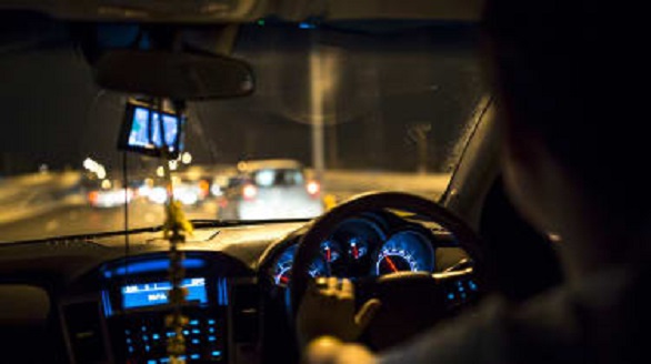 Pengemudi travel melaju di jalan tol pada malam hari dilihat dari dalam kabin kendaraan