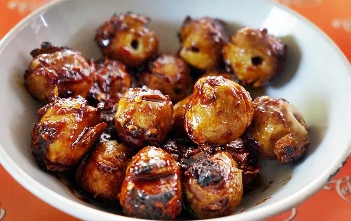 Bakso bakar berlumur bumbu kecap manis pedas dalam mangkuk putih