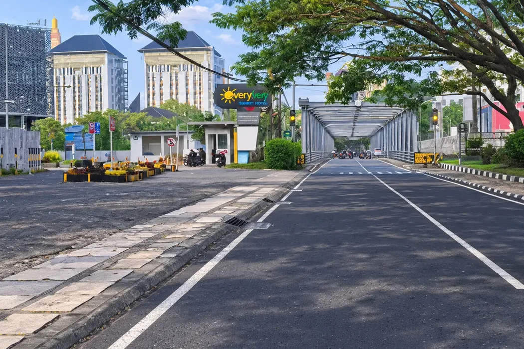 Jalan Soekarno-Hatta Malang yang teduh oleh pepohonan dengan Jembatan Suhat dan gedung bertingkat di latar belakang