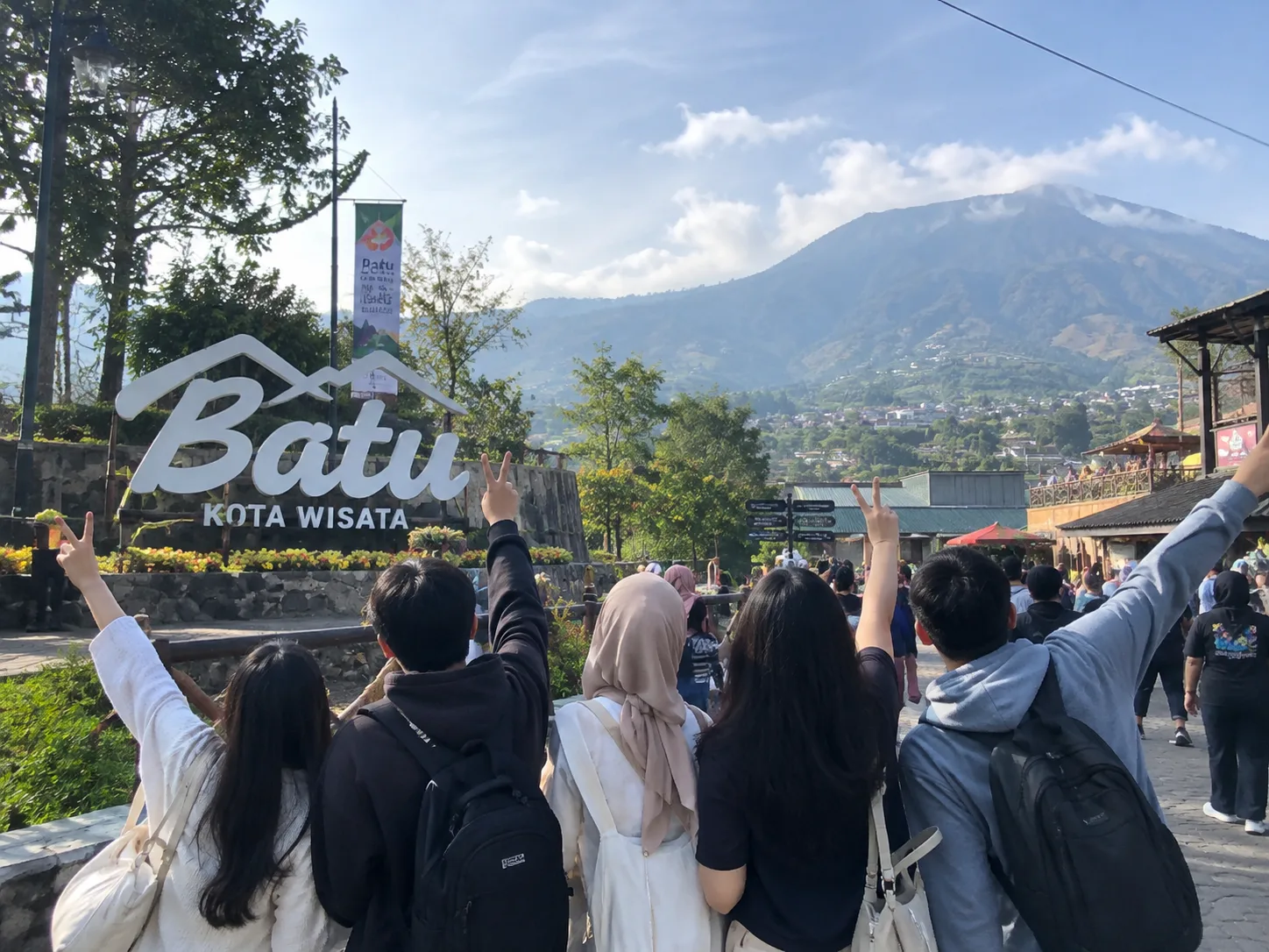 Sekelompok teman berpose di depan tulisan Batu Kota Wisata dengan latar pegunungan